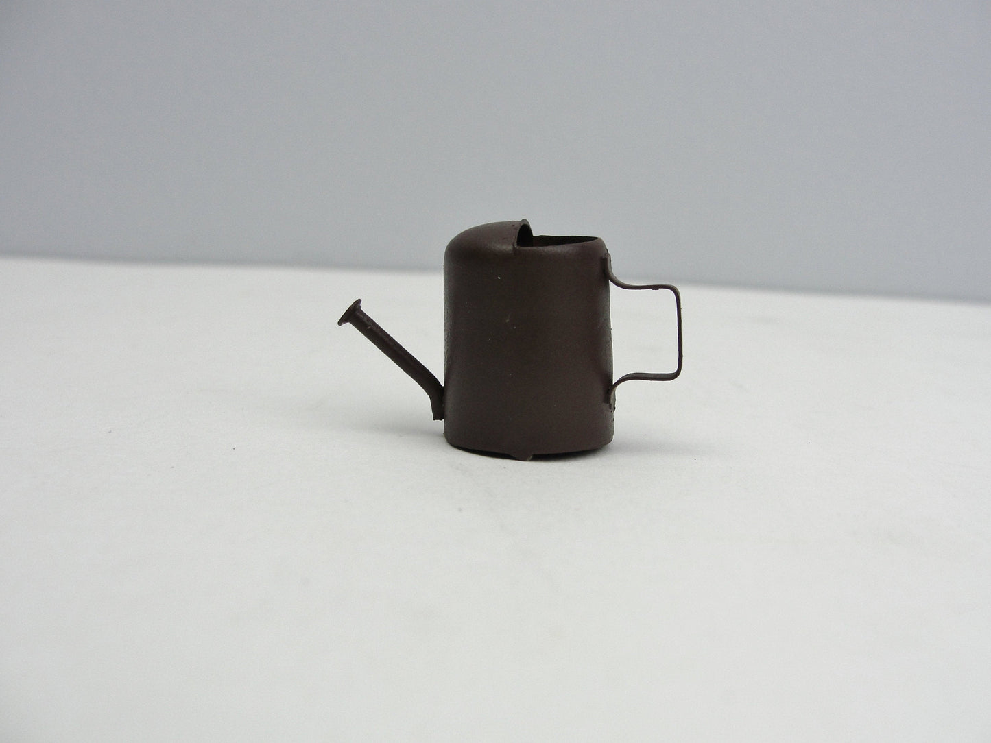 Miniature rust colored metal watering can